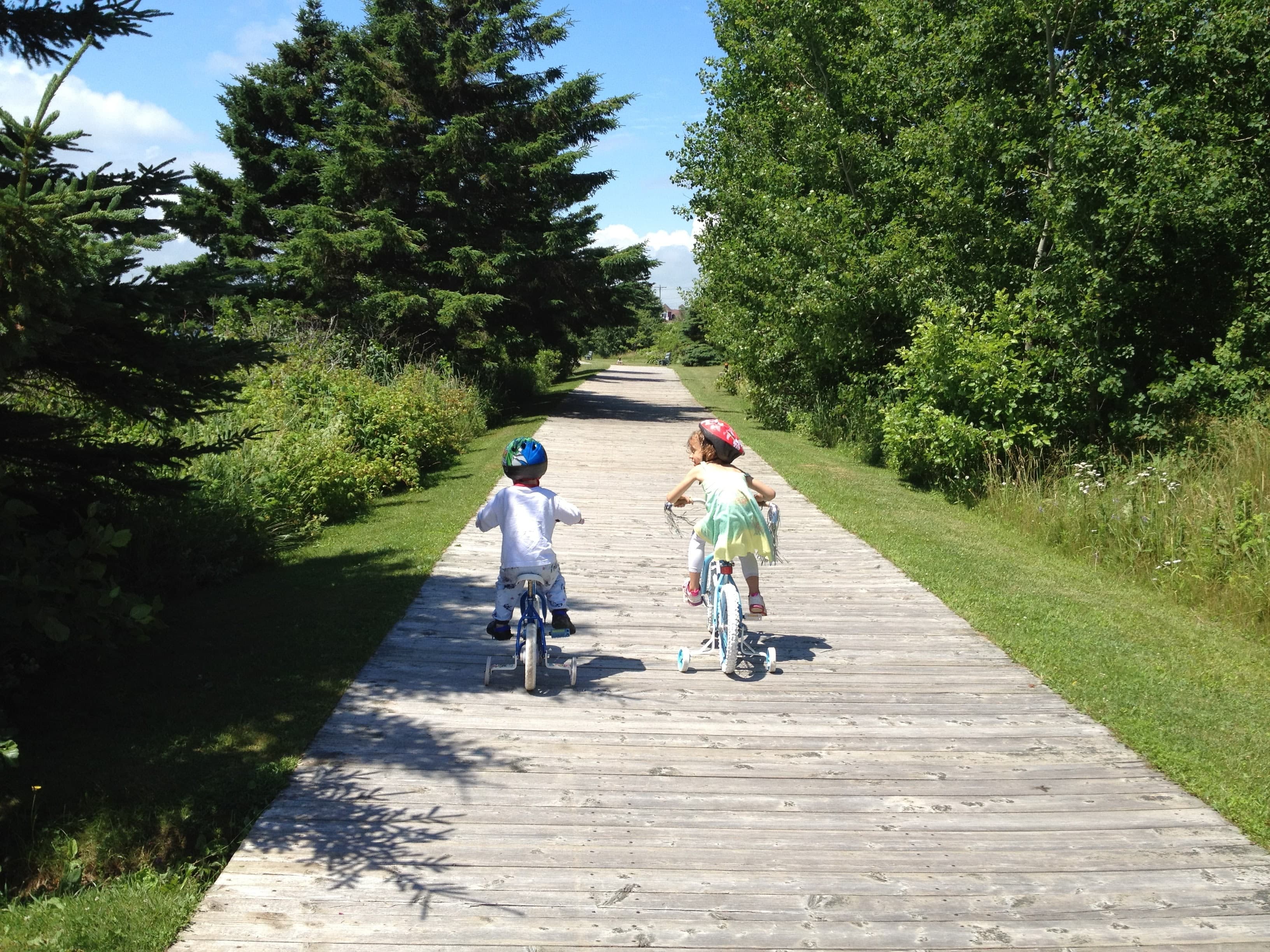 Two children riding bicycles on the North Rustico boardwalk